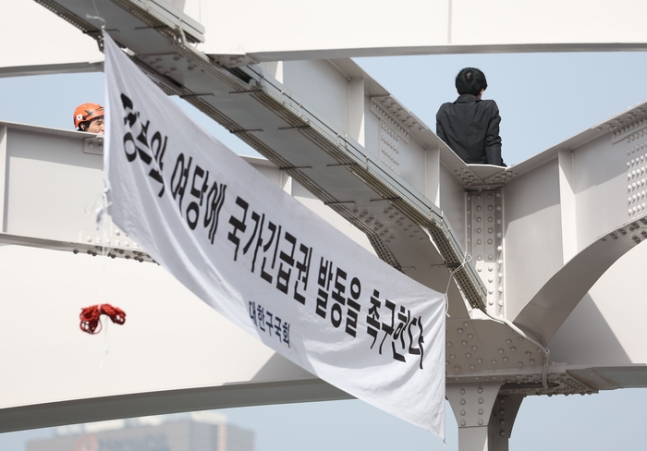  신원불명의 남성이 17일 오전 서울 용산구 한강대교 아치 위에 올라가 있다. [사진 출처 = 연합뉴스]