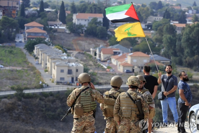 레바논과 이스라엘 국경 마을 카프르 킬라에서 한 남성이 팔레스타인과 헤즈볼라 깃발을 흔들고 있다./AP