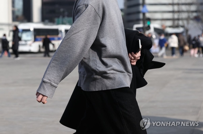 서울 광화문광장에서 한 시민이 외투를 들고 걸어가고 있다. [연합뉴스 자료사진]