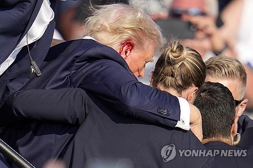 피격 후 경호원들에 둘러싸여 무대에서 내려가는 트럼프 전 대통령
[AP=연합뉴스 자료사진. 재판매 및 DB 금지]