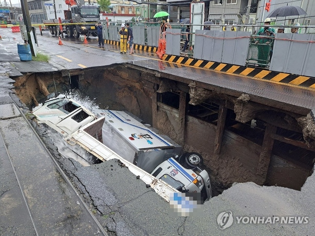 부산 대형 싱크홀 (부산=연합뉴스) 21일 오전 8시 45분께 부산 사상구 한 도로에서 가로 10ｍ, 세로 5ｍ, 깊이 8m가량의 대형 싱크홀이 발생해 트럭 2대가 빠져있다. 2024.9.21 [부산소방본부 제공.