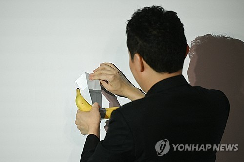 29일 홍콩 페닌술라 호텔서 바나나를 벽에서 떼고 있는 저스틴 선  [AFP=연합뉴스]