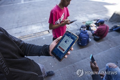 CBP 어플 보여주는 미국 입국 희망 이주자 [AP 연합뉴스 자료사진.재판매 및 DB 금지]