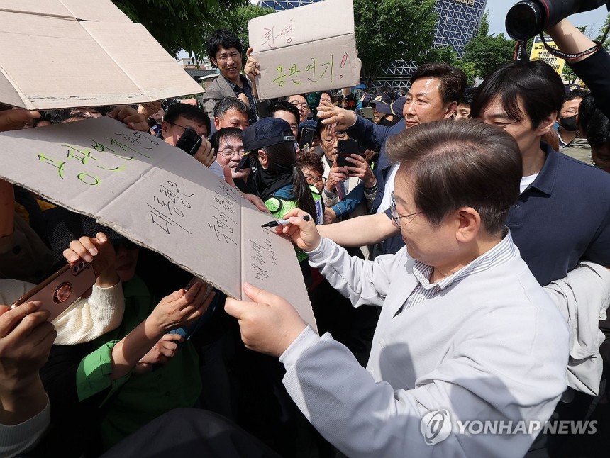 공판 연기 환영 팻말에 이재명 후보 '맞습니다' (전주=연합뉴스) 류영석 기자 = 더불어민주당 이재명 대선 후보가 '골목골목 경청투어:국토종주편'에 나선 7일 전북 전주시 풍남문 앞 광장에서 지지자들에게 인사를 하던