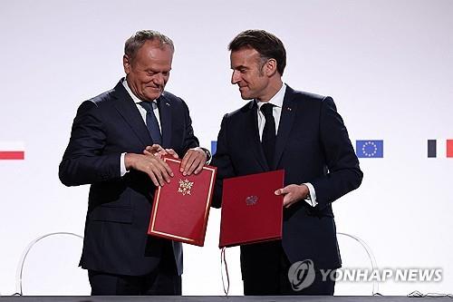 폴란드-프랑스 우호 조약 (낭시 AFP=연합뉴스) 도날트 투스크 폴란드 총리(왼)와 에마뉘엘 마크롱 프랑스 대통령이 9일(현지시간) 프랑스 낭시에서 상호 우호 조약을 맺었다.2025.05.09.