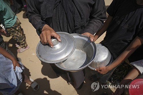 식량 바닥난 가자지구 (가자지구 칸유니스 AP=연합뉴스) 2025년 5월 9일 가자지구 남부 칸유니스의 한 급식소에서 식재료가 바닥나자 한 여성이 비어 있는 그릇을 열어 보고 있다.(AP Photo/Abdel Ka