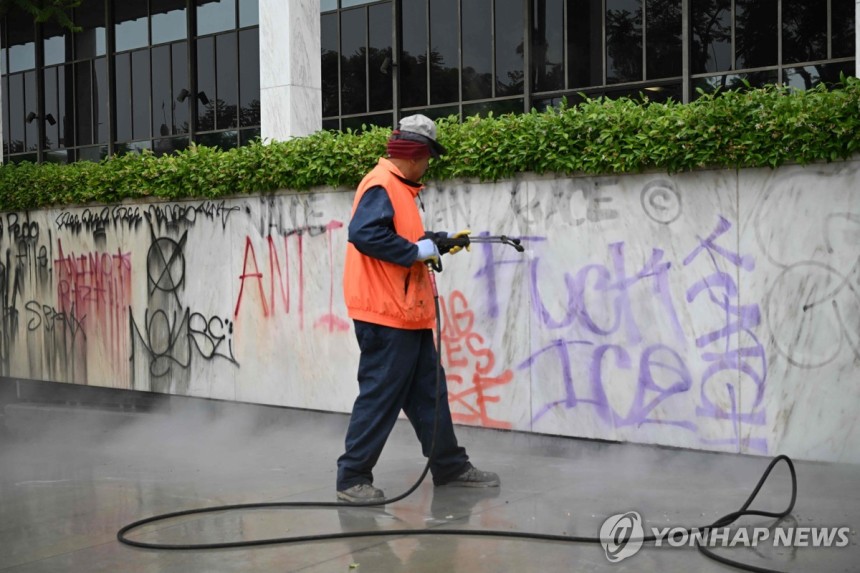 9일 오전 LA 도심에서 시위대가 남긴 낙서를 지우는 청소 노동자
[AFP=연합뉴스. 재판매 및 DB 금지]