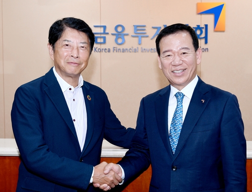 Koichi Matsushita (L), chairman of the Japan Investment Trusts Association, shakes hands with Seo Ye