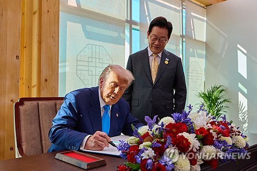 President Lee Jae Myung (R) watches U.S. President Donald Trump signing a guest book at the Gyeongju