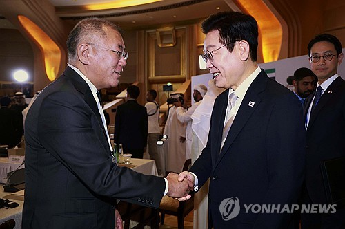 President Lee Jae Myung (R) shakes hands with Hyundai Motor Group Chairman Euisun Chung during a bus