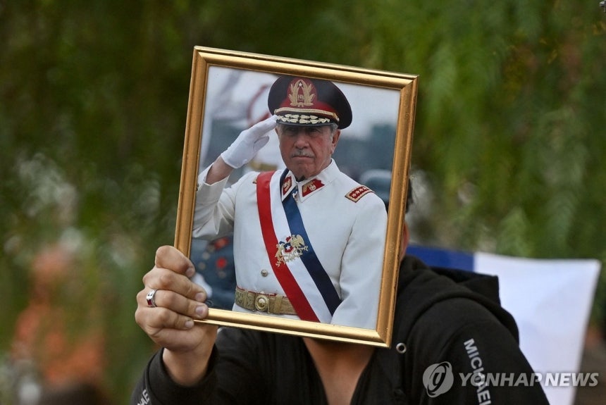 14일(현지시간) 칠레 군부 독재자 피노체트 사진 들고 나온 주민 [산티아고 AFP=연합뉴스.재판매 및 DB 금지]