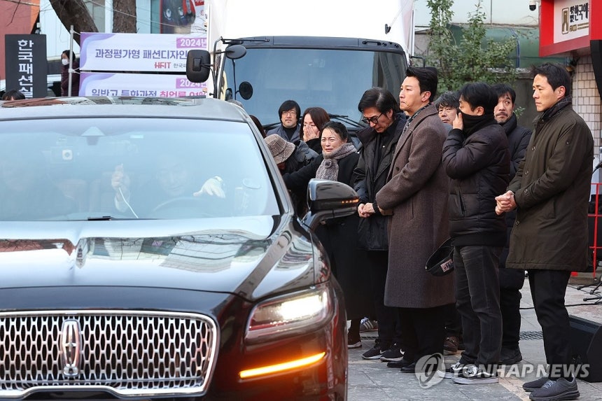 윤석화 마지막 가는 길 (서울=연합뉴스) 강민지 기자 = 21일 서울 종로구 한예극장 앞에서 열린 배우 윤석화의 노제에서 동료들이 운구차를 배웅하고 있다.2025.12.21 