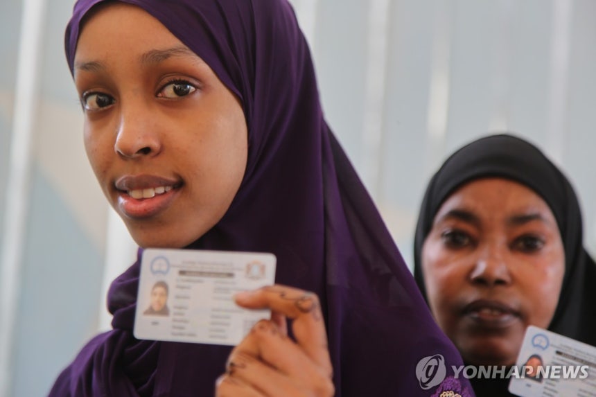 25일 소말리아 모가디슈에서 투표를 위해 선 주민들이 신분증을 보여주고 있다.[AP=연합뉴스]