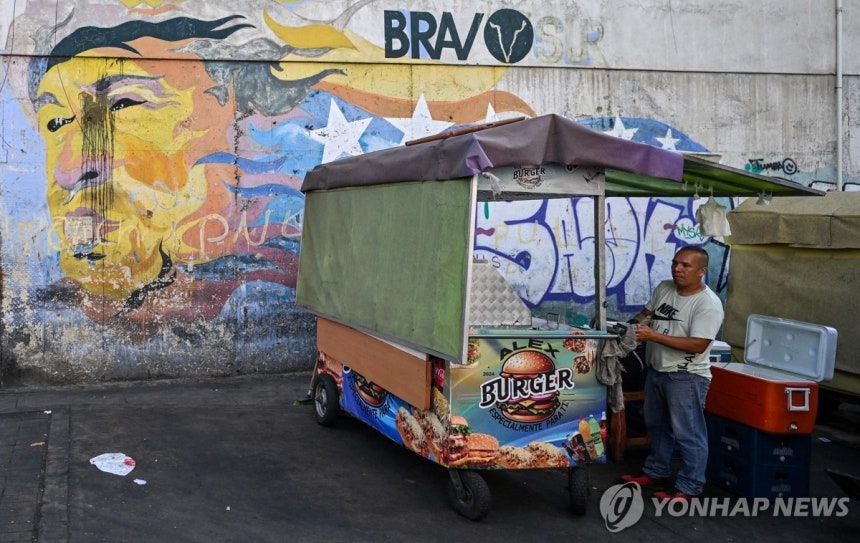 지난해 12월 29일(현지시간) 차베스 벽화 앞에서 햄버거 파는 상인 [카라카스 AFP=연합뉴스.재판매 및 DB 금지]