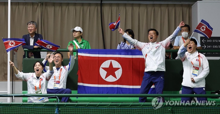 남북 대결…북측 환호(히가시야마[일본]=연합뉴스) 김동민 기자 = 23일 일본 히가시야마공원 테니스센터에서 열린 2026 아이치·나고야 아시안게임 정구 여자 단식 8강 한국 황정미와 북한 리진미의 경기. 북한 리진미가 득점하자 북한 관계자들이 인공기를 흔들며 기뻐하고 있다. 2026.9.23 image@yna.co.kr
