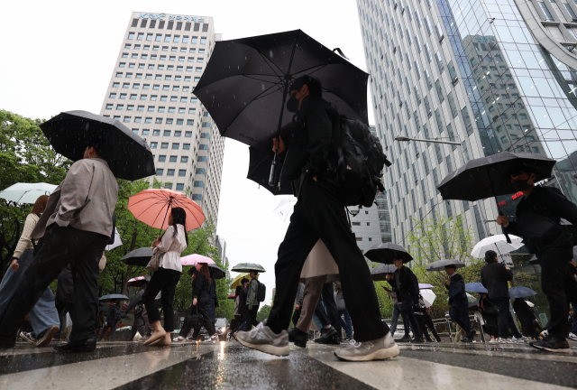 ▲雨が降った15日午前、ソウル永登浦区汝矣島駅近くで市民が傘を使って移動している。 ⓒヨンハップニュース