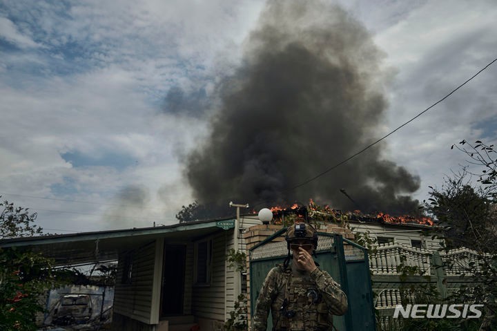 불 타는 가옥 앞 지나는 <b>우크라이나</b> 군인