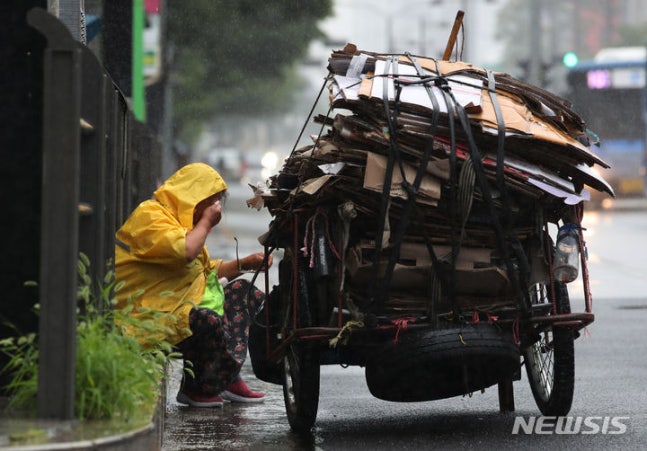 [Seoul=Newsis] Reporter Go Seung-min = An elderly man collecting recyclables on a street in Seongbuk-gu, Seoul on June 26, when it rained heavily in most parts of the country. The elderly man is taking a rest by the roadside after loading the recyclables on a cart. 2023.06.26. kkssmm99@newsis.com