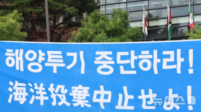 [Seoul=Newsis] Reporter Kim Geum-bo = Environmental activists from the Environmental Movement Union carry a banner urging to stop ocean dumping of contaminated water across from the Japanese embassy in Jongno-gu, Seoul on August 21, the first anniversary of the release of contaminated water from the Fukushima nuclear power plant. A Japanese flag is visible behind the banner.