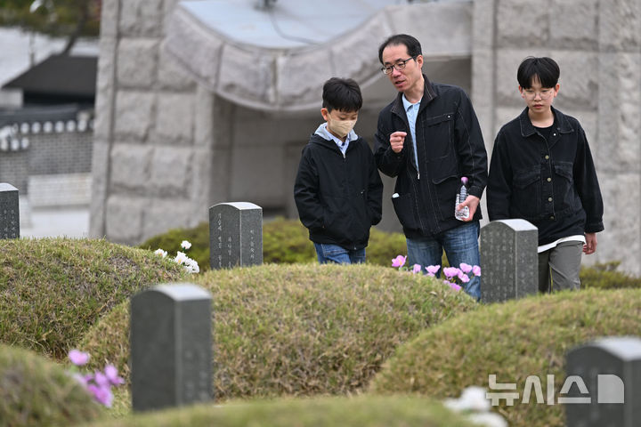 [광주=뉴시스] 이영주 기자 = 5·18민주화운동 45주기를 12일 앞둔 6일 오전 광주 북구 운정동 국립5·18민주묘지에서 한 추모객이 아들들에게 5·18 당시 숨진 희생자들의 사연을 설명해주고 있다.2025.0