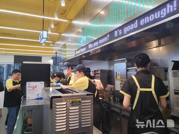 [서울=뉴시스] 서울시 코엑스 내 노브랜드 버거 매장에서 직원들이 가성비 신메뉴 라인인 'NBB어메이징 버거'를 만들고 있다.