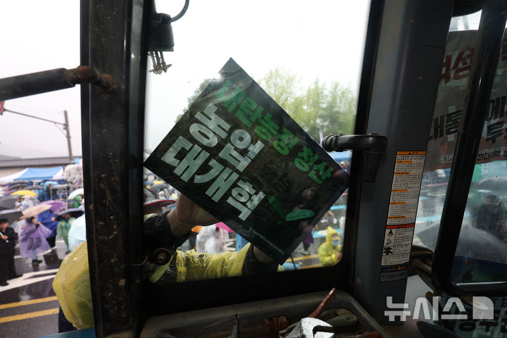 [서울=뉴시스] 김명년 기자 = 10일 오후 서울 종로구 경복궁 동십자각 인근에서 열린 내란청산·사회대개혁 비상행동 주최 사법부 정치개입 규탄 집회에서 한 농민이 도착한 전국농민회총연맹 트랙터에 피켓을 붙이고 있다.