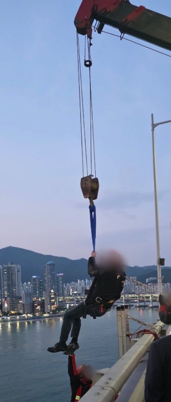 [부산=뉴시스] 11일 부산 광안대교 상판 난간에 들어가 고공시위를 벌인 A(50대)씨가 크레인으로 구조되고 있다.(사진=부산경찰청 제공) 2025.05.11.*재판매 및 DB