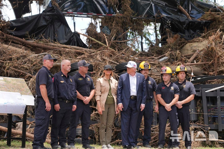 [커빌(텍사스주)=AP/뉴시스]도널드 트럼프 미국 대통령이 멜라니아 여사와 11일(현지 시간) 미 텍사스주 커빌의 홍수 피해 지역을 방문해 수색대원 등과 기념촬영을 하고 있다. 2025.07.12.