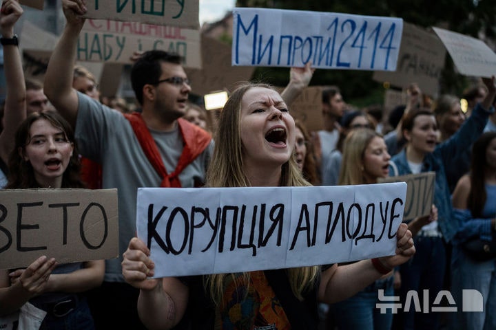 [키이우=AP/뉴시스]22일(현지시각) 밤 우크라이나 수도 키이우의 마이단 광장에서 벌어진 시위에서 볼로디미르 젤렌스키 대통령 정부의 반부패기관 무력화 조치에 항의하는 한 여성이 "부패 조장"이라고 쓴 피켓을 들고
