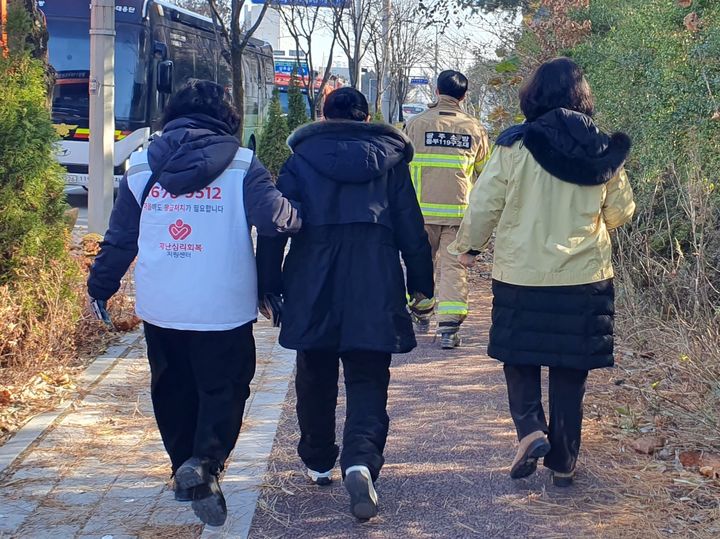 [광주=뉴시스] 이현행 기자 = 12일 낮 광주 서구 광주대표도서관 붕괴 현장에서 매몰된 작업자 가족이 재난심리회복 지원 인력의 부축을 받으며 걷고 있다.2025.12.12.*재판매 및