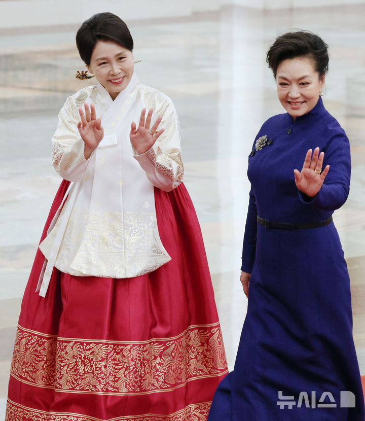 [베이징=뉴시스] 최동준 기자 = 이재명 대통령과 중국을 국빈 방문한 김혜경 여사가 펑리위안 여사와 함께 5일(현지 시간) 베이징 인민대회당에서 열린 공식환영식에서 손을 흔들며 이동하고 있다. 2026.01.05. 