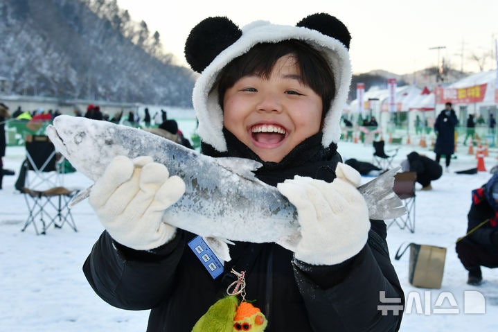 [화천=뉴시스]서백 기자=주말을 맞은 11일 화천산천어축제장을 찾은 한 아이가 얼음낚시터에서 잡은 산천어를 들어 올리며 기뻐하고 있다.(사진=화천군 제공) 2026.01.11.