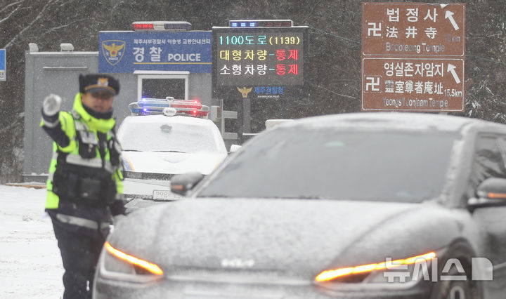 [제주=뉴시스] 우장호 기자 = 제주 산지·중산간·동부·남부에 대설특보가 내려진 11일 오전 제주시 어승생 삼거리 입구에서 제주서부경찰서 소속 경찰관이 도로통제를 하고 있다.기상청에 따르면 제주도는 12일까지 한라
