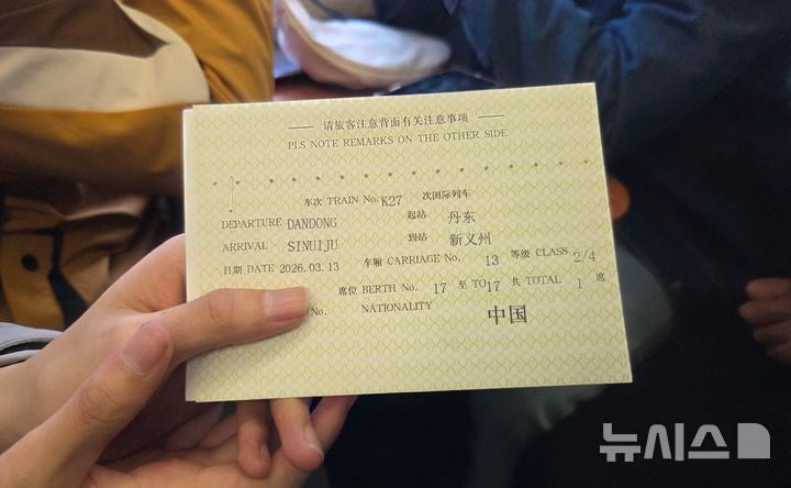 [베이징=뉴시스] 박정규 특파원 = 12일 중국 베이징에서 북·중 간 여객열차 운행이 재개된 가운데 이날 평양행 열차인 K27편에 탑승한 한 중국인 대학생이 목적지가 신의주라고 써있는 증서를 들어보이고 있다.202