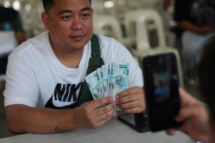 [케손시티=AP/뉴시스] 24일(현지 시간) 필리핀 케손시티에서 교통네트워크차량서비스(TNVS) 운전자들이 정부로부터 생계 지원 현금을 받고 있다. 필리핀 정부는 유가 상승에 대응