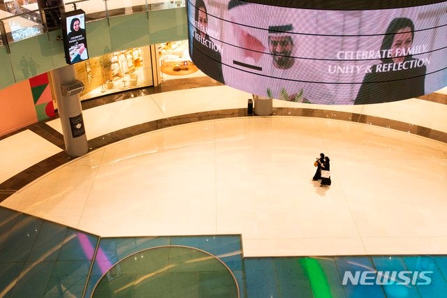 [두바이=AP/뉴시스]11일(현지시간) 아랍에미리트(UAE) 두바이의 텅 빈 두바이 쇼핑몰에서 신종 코로나바이러스 감염증(코로나19) 예방을 위해 마스크를 쓴 두 여성이 커피를 들고 지나가고 있다.두바이를 비롯한 