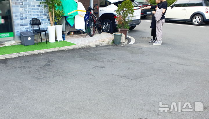 [창원=뉴시스] 강경국 기자 = 지난 27일 오전 경남 창원시의 한 아파트 상가 주차장에서 칼부림 사건이 발생한 가운데 28일 오후 행인들이 사고 현장을 가리키고 있다. 2026.