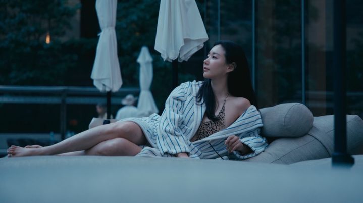 プールサイドのソファで白いガウンを羽織り、レオパード柄の水着を着たキム・サラン