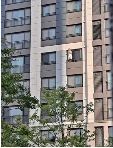 고층 아파트 창틀에 올라서서 담배를 피우는 남성. 온라인 커뮤니티 캡처
