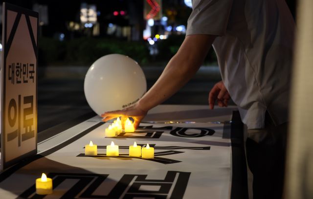전라북도특별자치도의사회가 30일 전북도청 앞에서 의대 증원 반대를 촉구하는 집회를 열고 '의료사망'이라고 쓴 글자 위로 촛불을 놓는 퍼포먼스를 하고 있다. 연합뉴스 