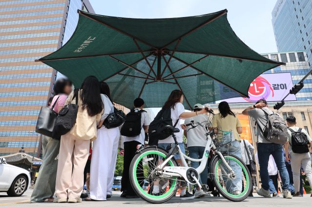 9일 서울 종로구 광화문 네거리에 설치된 그늘막 아래 시민들이 모여있다. 올여름 최고기온이 33도 이상인 폭염일이 평년보다 많을 것이라는 전망이 나온다. 연합뉴스