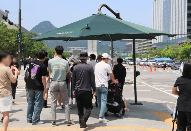  9일 서울 종로구 광화문 네거리에 설치된 그늘막 아래 시민들이 모여있다. 연합뉴스