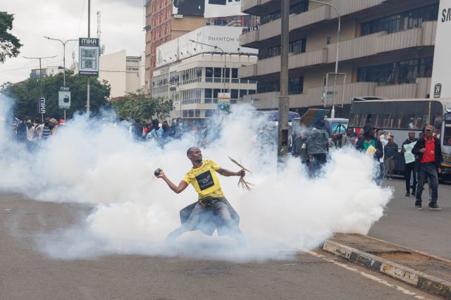 케냐 수도 나이로비에서 20일(현지시간) 증세 반대 시위에 참가한 한 남성이 최루탄을 집어 들어 경찰 쪽으로 던지고 있다. AFP연합뉴스