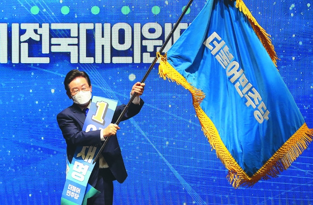 이재명 더불어민주당 대표가 2년 전인 2022년 8월 28일 서울 송파구 올림픽 체조경기장에서 열린 정기전국대의원대회에서 새 당대표로 선출된 뒤 당기를 흔들고 있다. 이 대표는 오는 8월 있을 전당대회에도 출마해 연