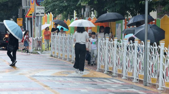 제주도에 장마가 시작된 지난 20일 오전 제주시 노형초등학교 통학로가 우산을 든 어린이들로 붐비고 있다. 연합뉴스