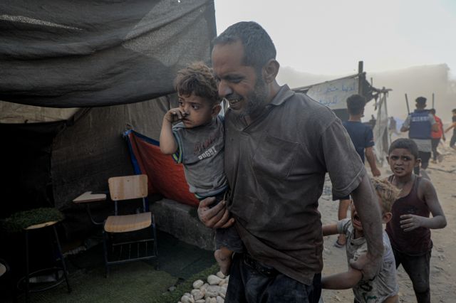 A Palestinian man holding his child evacuates as Israel strikes the southern Gaza Strip city of Khan Yunis on the 3rd (local time). News1