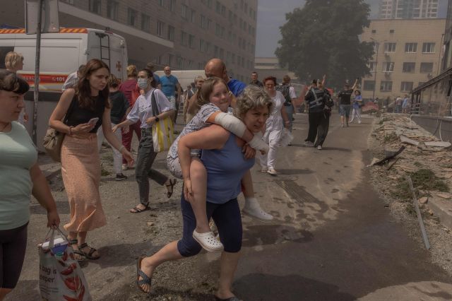 한 우크라이나 여성이 8일(현지시간) 러시아의 미사일 공격으로 파괴된 오흐마트디트 아동병원 건물 인근에서 어린 아이를 안은 채 대피하고 있다. AFP연합뉴스 