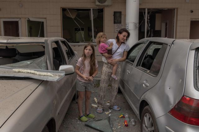 한 우크라이나 여성이 8일(현지시간) 러시아의 미사일 공격으로 파괴된 오흐마트디트 아동병원 건물 주차장에서 자식들과 함께 대피해 있다. AFP연합뉴스 
