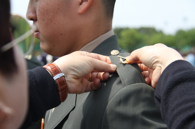 지난해 5월 12일 경북 포항 해병대 교육훈련단에서 열린 해병대 부사관 400기 임관식에서 한 후보생 부모가 아들에게 하사 계급장을 달아주고 있다. 기사의 이해를 돕기 위한 사진. 뉴시스