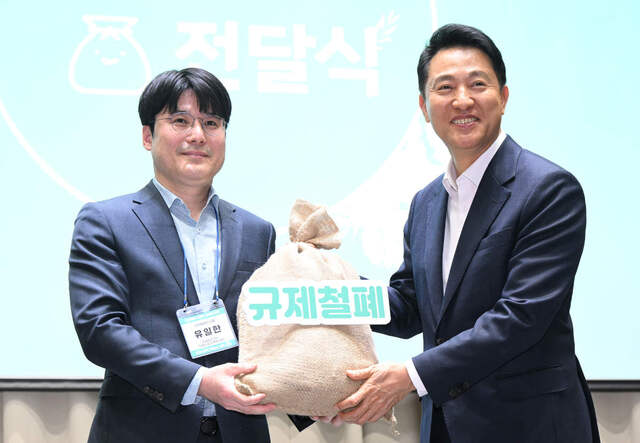 오세훈 서울시장이 7일 열린‘규제철폐 100일 성과보고회’에서 시민들의 규제철폐 제안이 담긴 규제철폐 모래주머니를 전달받고 있다.서울시 제공